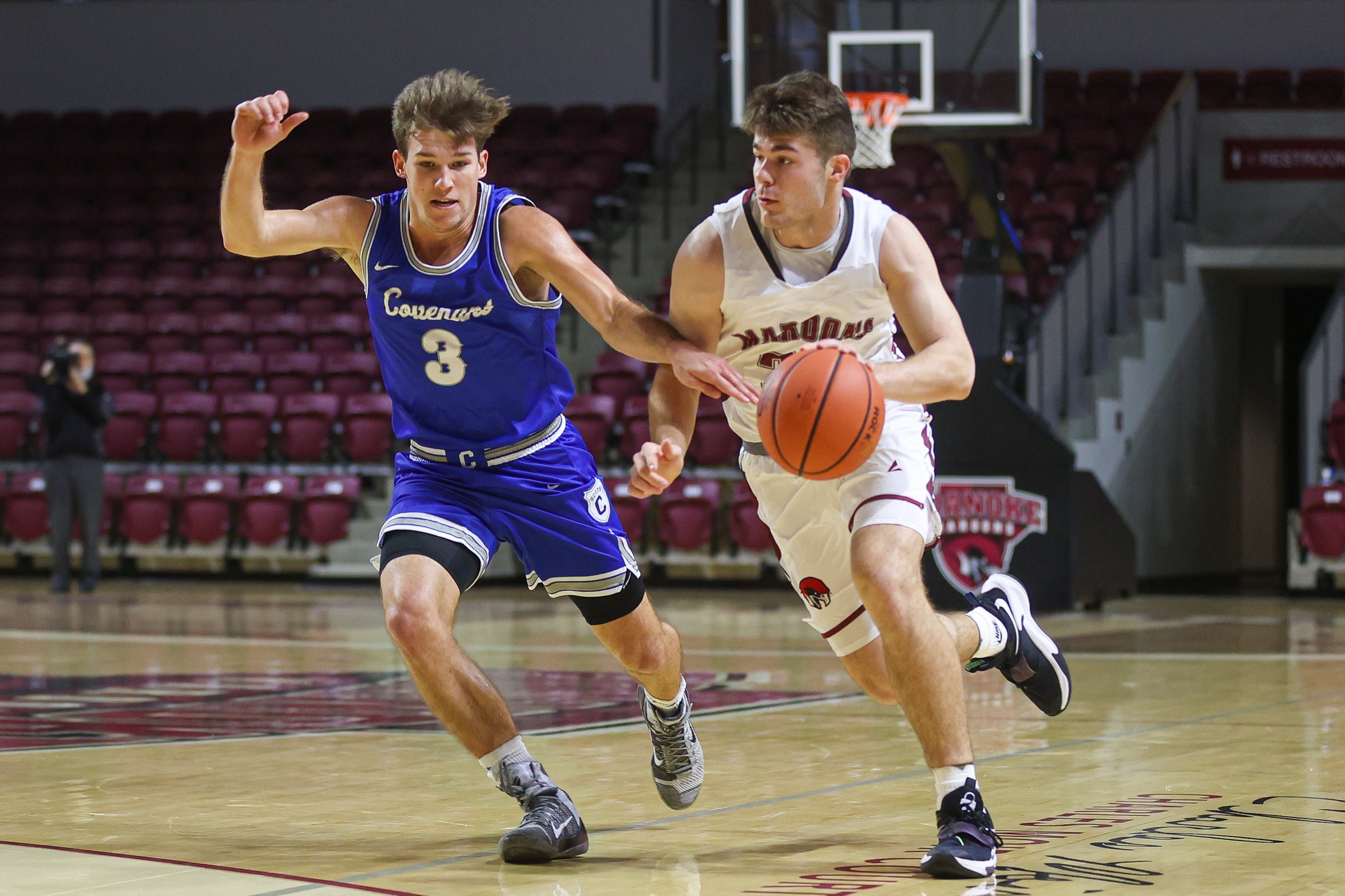 action photo of RC men's basketball player Kasey Draper dribbling passed a defender