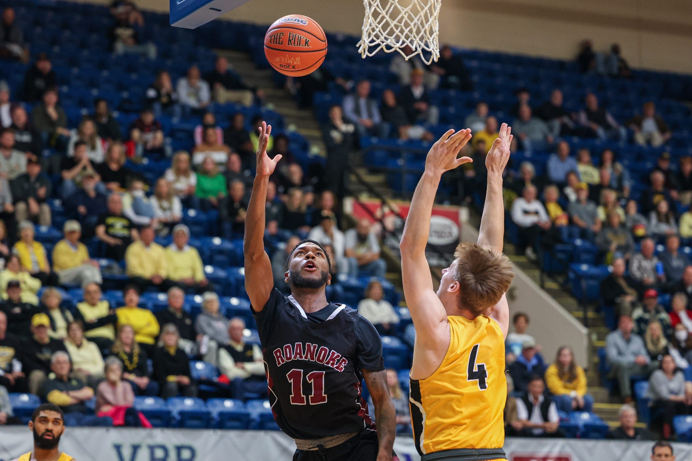 action photo of RC men's basketball player shooting against a defender