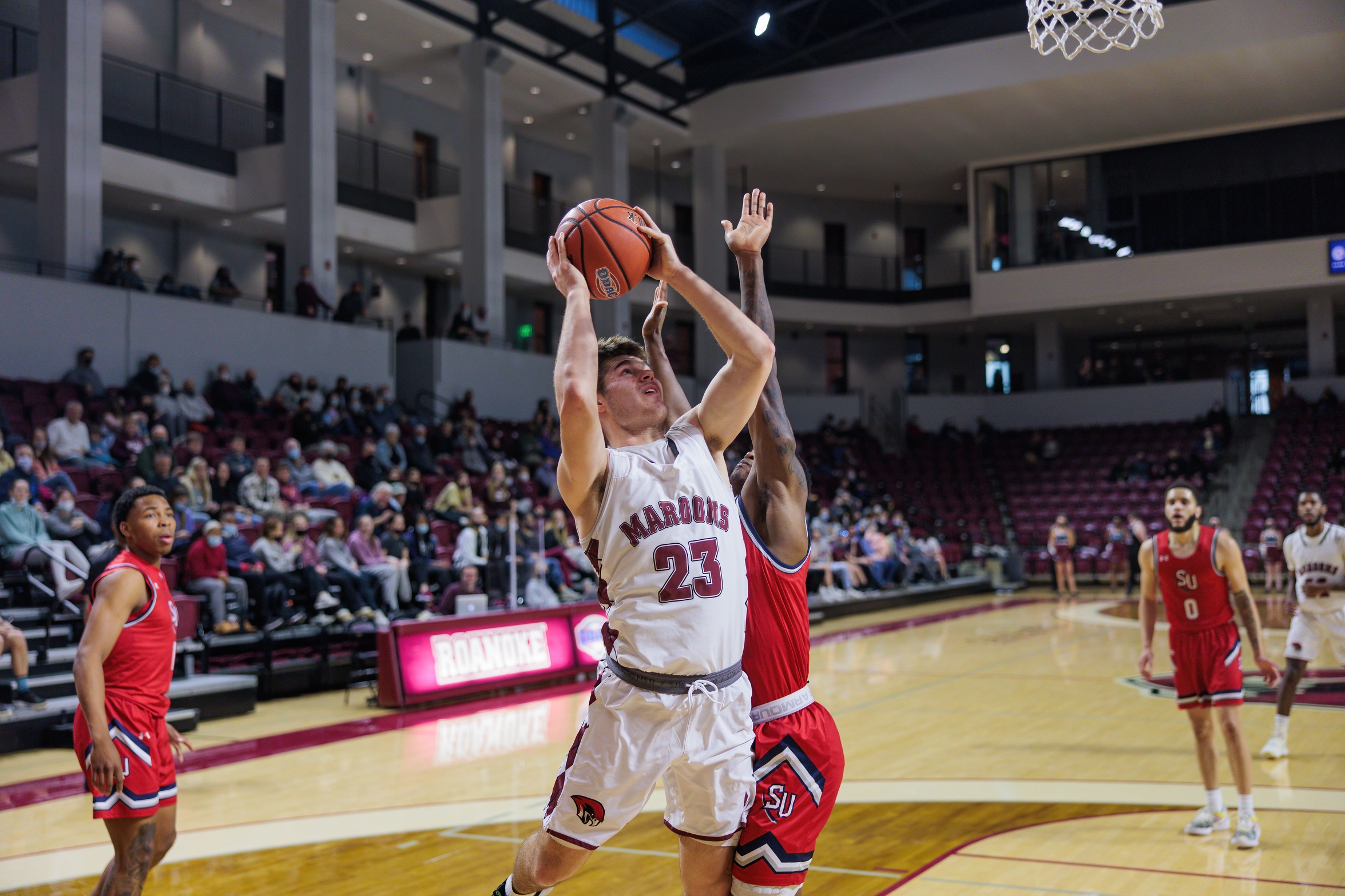 action photo of RC men's basketball player Kasey Draper going up against a defender at the basket 