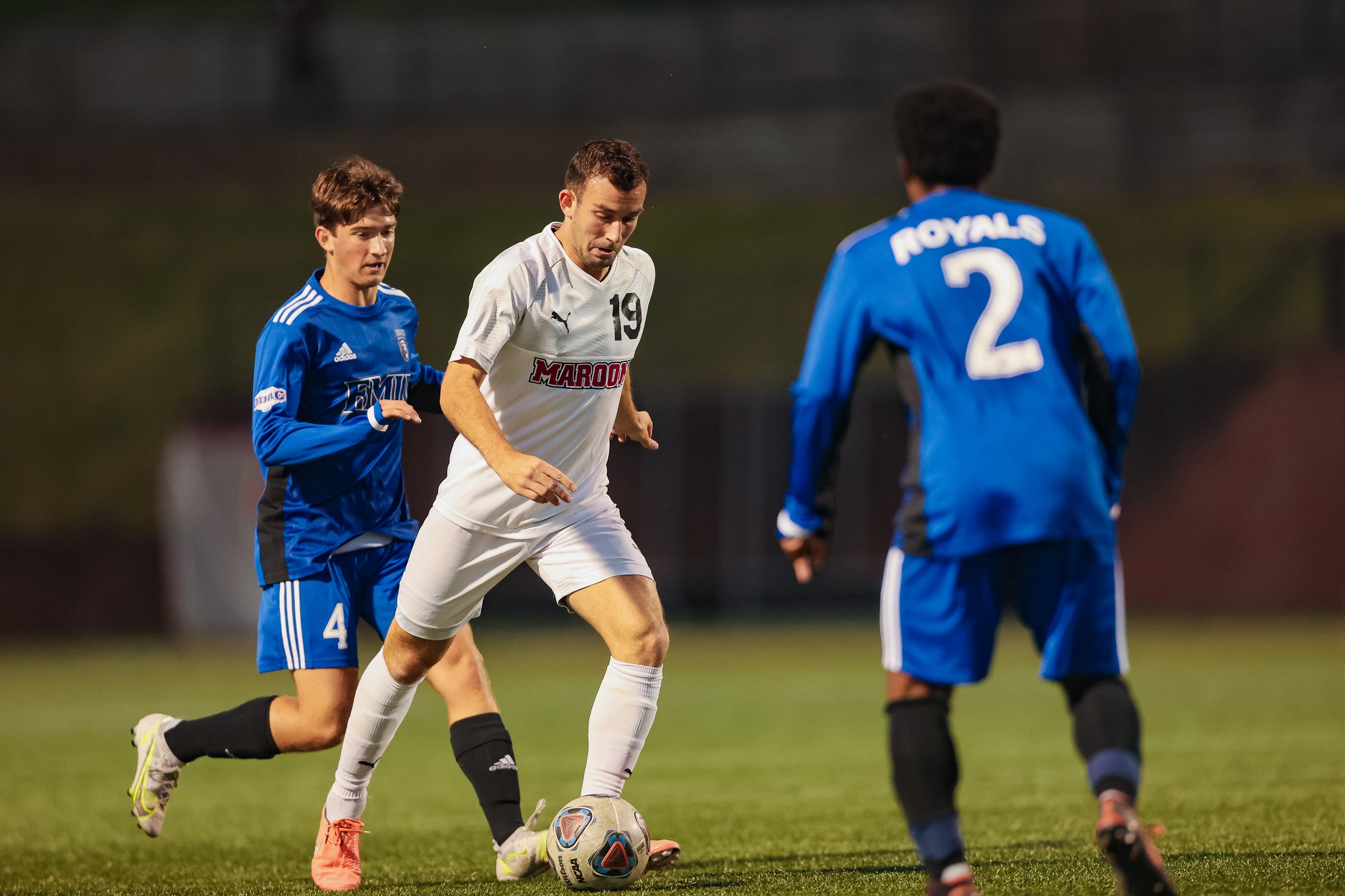 action photo of RC men's soccer player Liam Camalleri splitting defenders