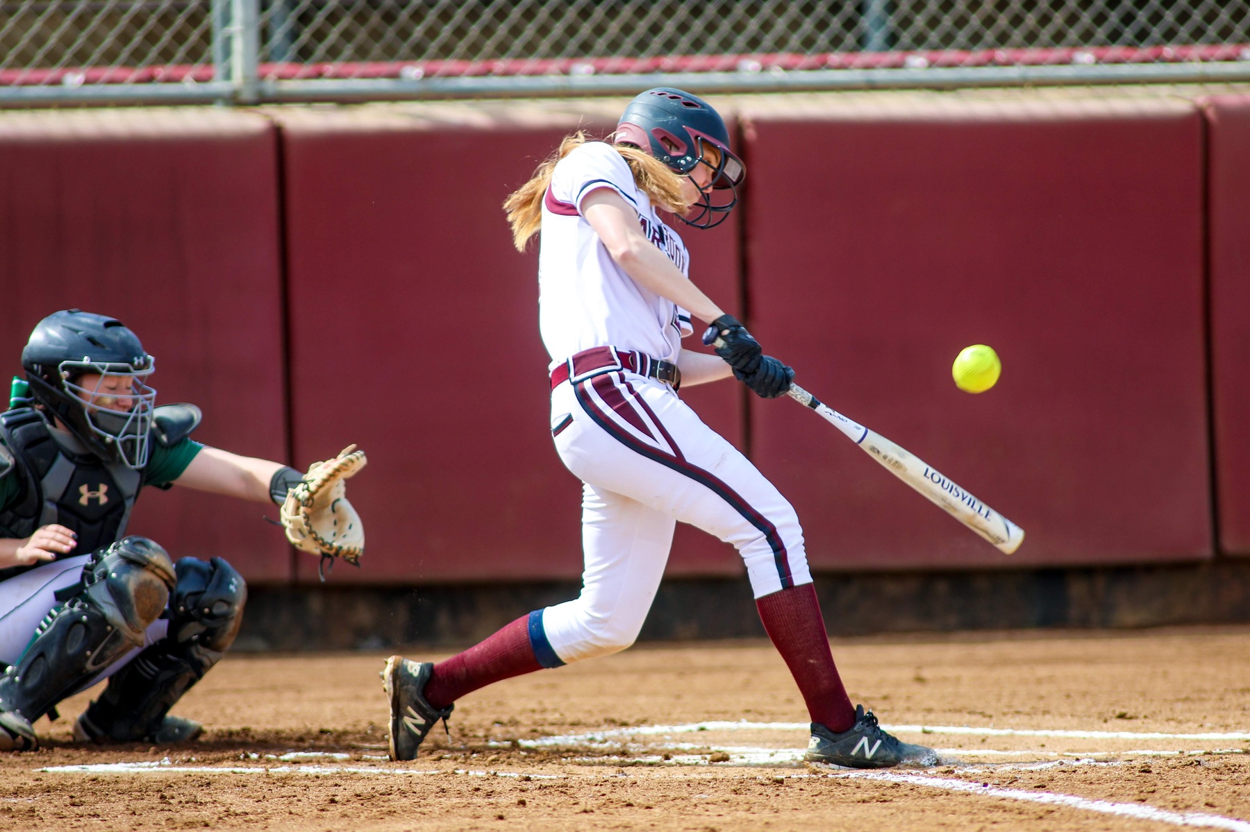action photo of RC softball player Rebecca Hensley hitting the ball