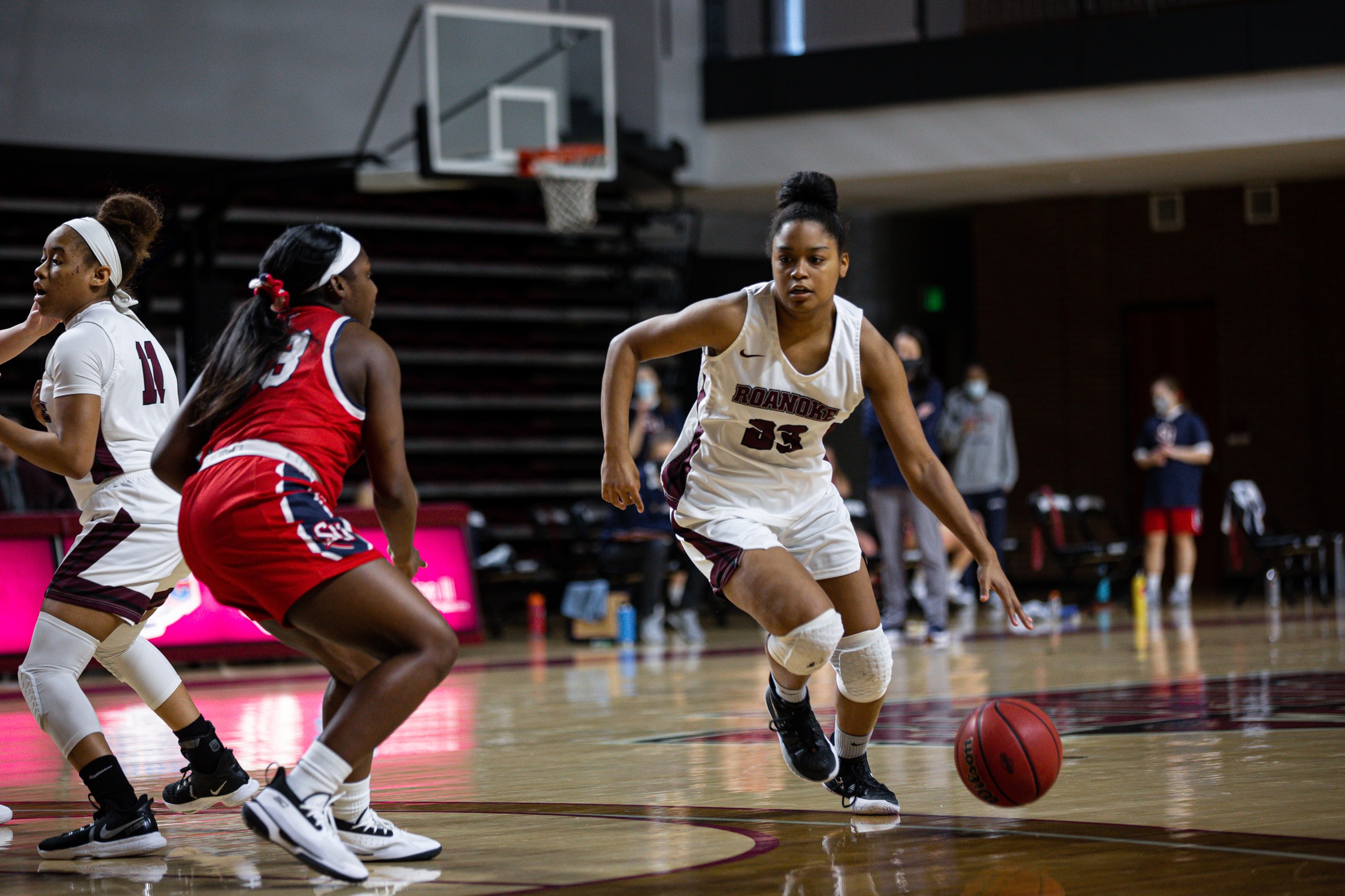 action photo of RC basketball player Ayanna Scarborough dribbling past a defender