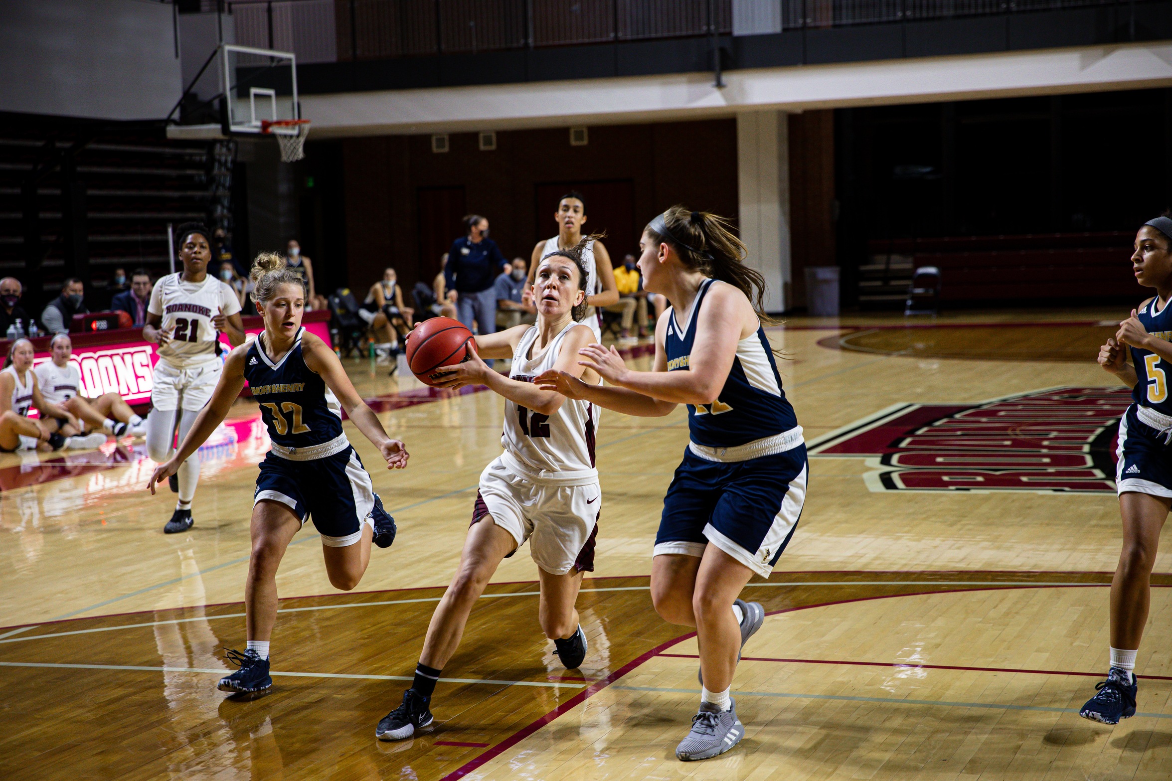 action photo of RC basketball player Kristina Harrel splitting defenders and driving to the basket