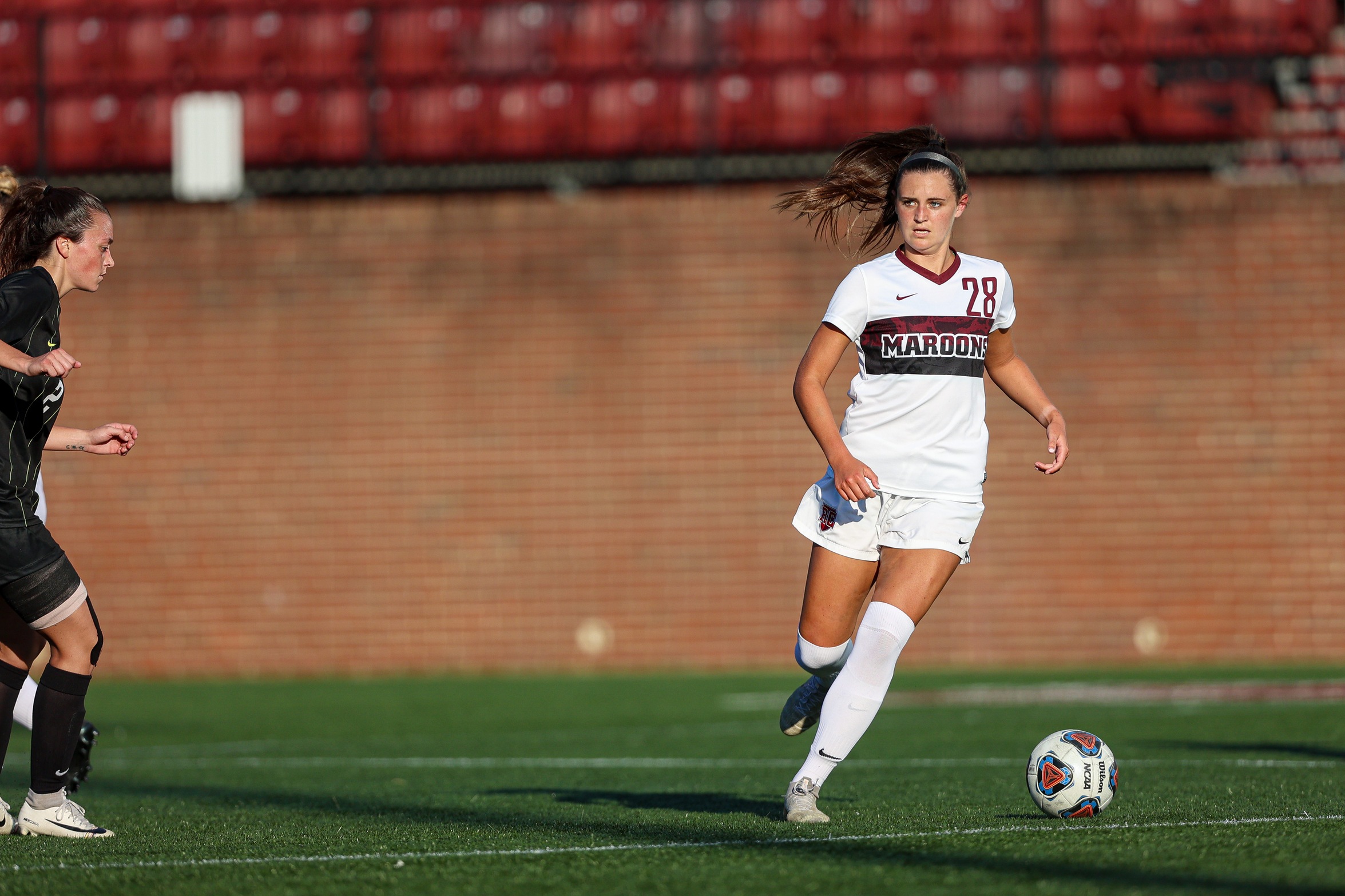 action photo of RC women's soccer player Emma Woods with the ball