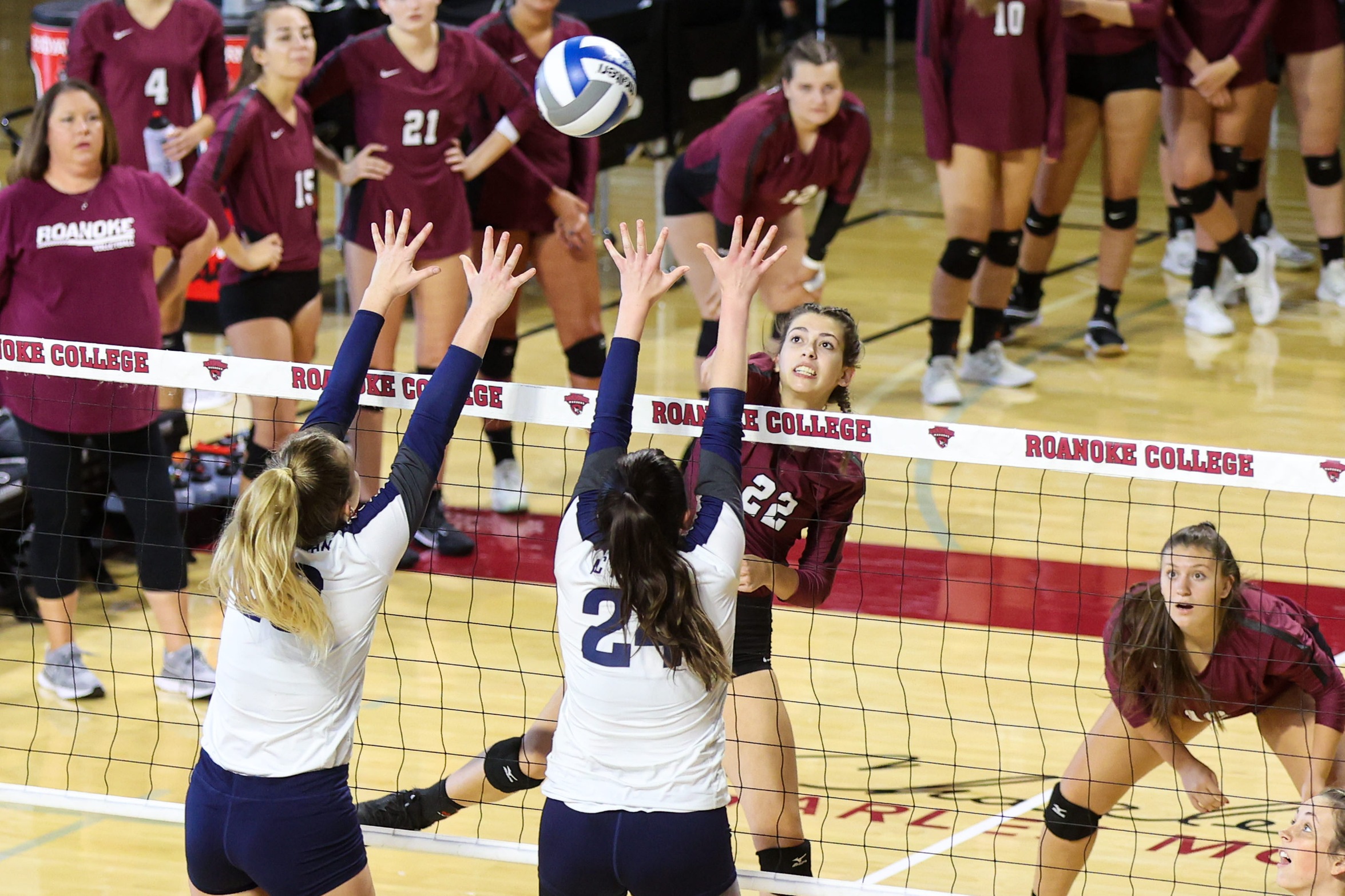 action photo of RC volleyball player Rylee Mayer attacking over two defenders
